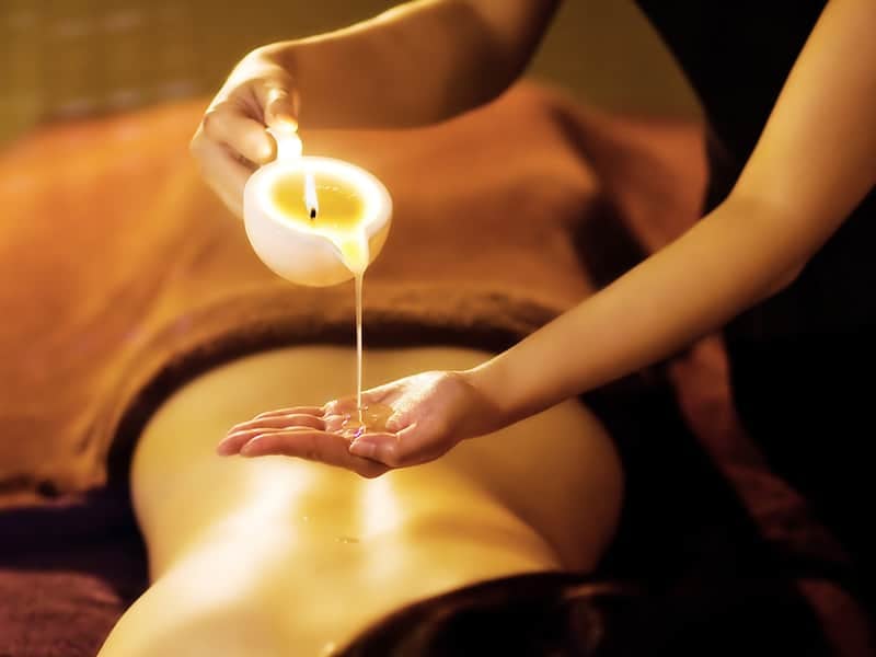 Warm candle massage oil poured into a client's hand – Lemon Zest Candle Massage, Reconnect Day Spa