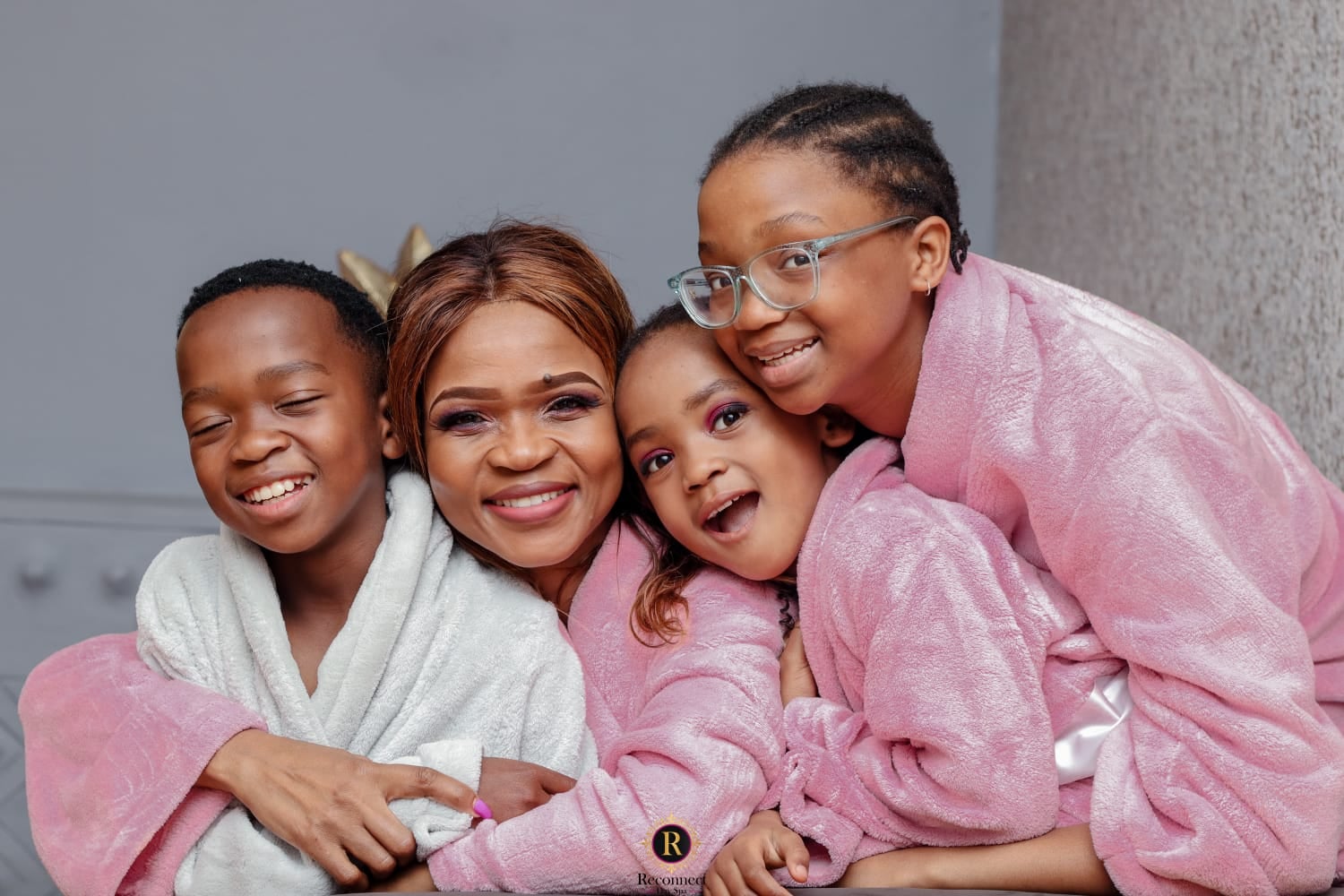 Mom and her children smiling together in spa robes – Mom & 2 Kids Spa Special, Reconnect Day Spa