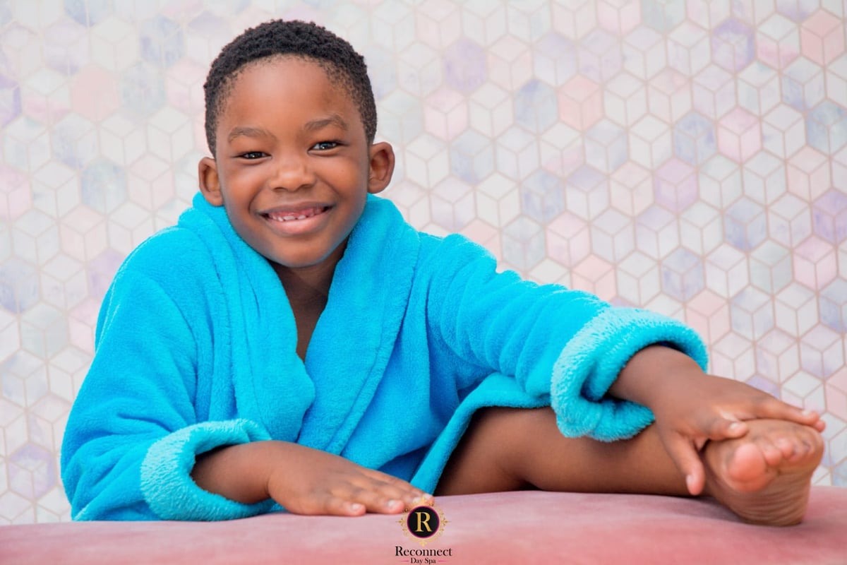 Girl with neatly braided hair in a pink spa robe, chin on her hands – Kids Big Spoil Spa Day for 1, Reconnect Day Spa