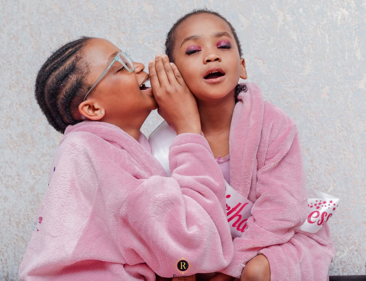 Two girls with braided hair in pink spa robes sharing a secret – Kids Sparty for 2, Reconnect Day Spa